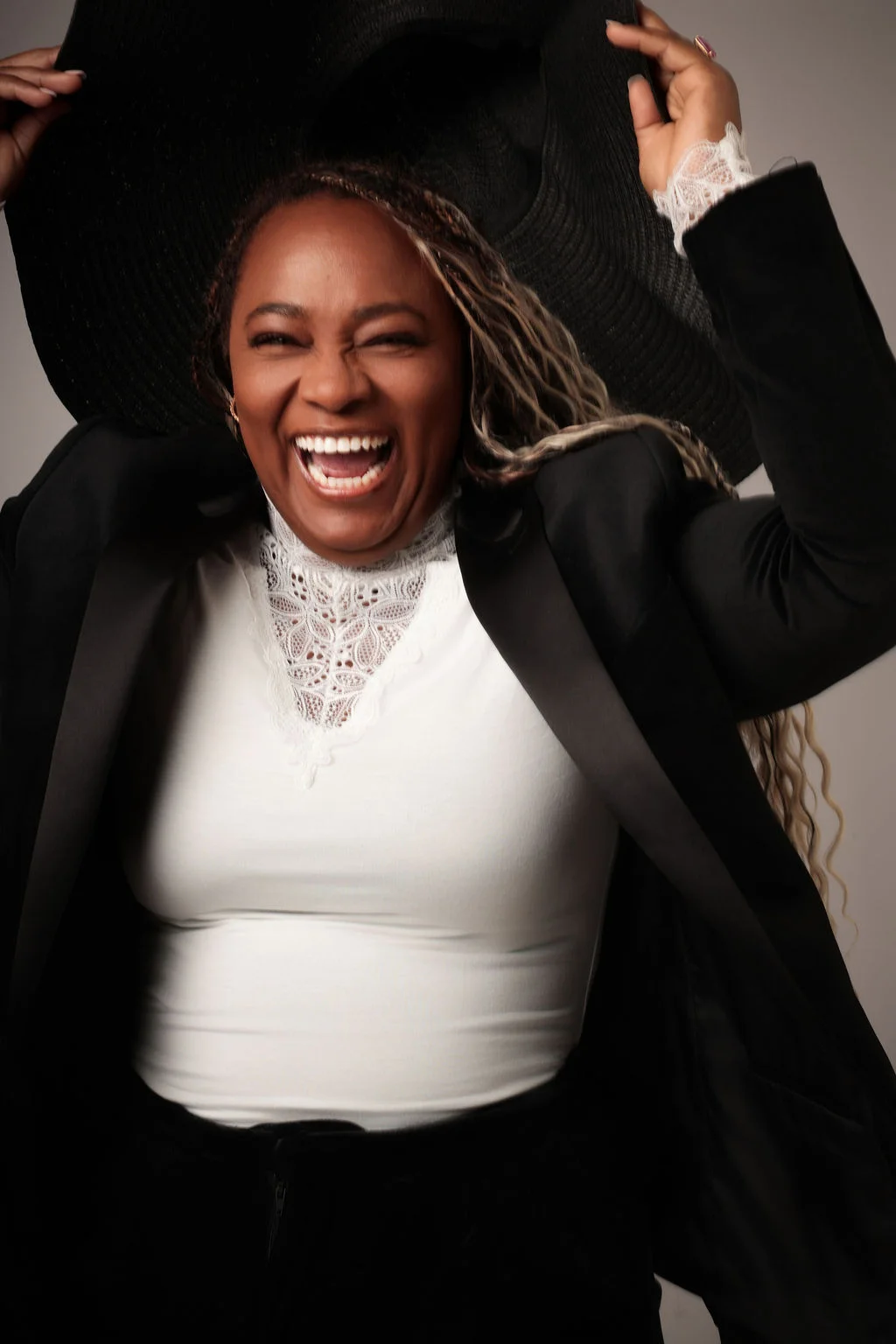 Nathalia laughing while holding a black hat above her head